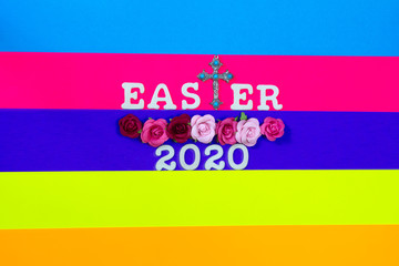 Multi colored bcakground with cross and flowers with the words Easter 2020