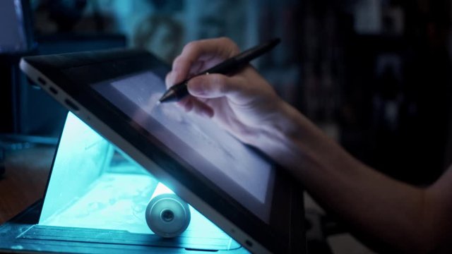 Young artist drawing illustration on tablet, slow motion, shallow depth of field