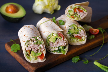 Turkey wraps with avocado, tomatoes and iceberg lettuce on chopping board. Tortilla, burritos, sandwiches, twisted rolls - obrazy, fototapety, plakaty