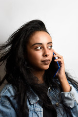 Beautiful middle eastern girl talking on the phone smiling on a white background.