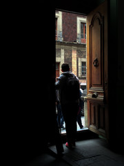 Hombre en habitaci&oacute;n oscura parado en la puerta mirando hacia la calle