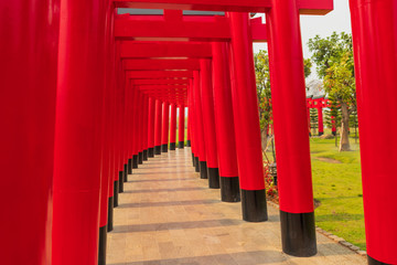 Walkway with red pillars to go green grass field and flower garden , Landscaping in the garden , Shaded walkway in the morning .