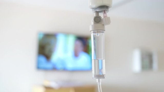 Close-up of Saline solution drip for patient and infusion pump on blurred luxury VIP room background in hospital.
