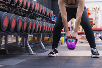 Young sporty woman doing Sumo squats with kettlebell in gym. Sport and exercise concept.