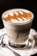A cup of Chai Latte on a white saucer against a dark background