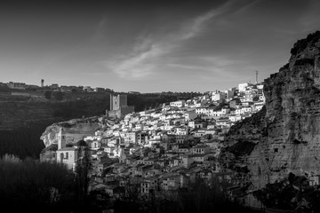 Black and white image of colorful houses with square windows and traditional roofs in Alcala del Jucar Spain