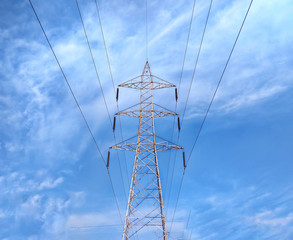 Single high-voltage post or tower isolated on cloudy blue sky background.