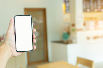 Mockup image blank white screen cell phone.man hand holding texting using mobile on desk at coffee shop.background empty space for advertise text.people contact marketing business,technology 