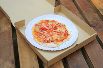 Delicious homemade Pizza in cardboard paper box on wooden table.