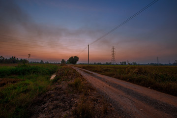 Blurred twilight evening background on rice paddies, with high voltage electricity towers passing...