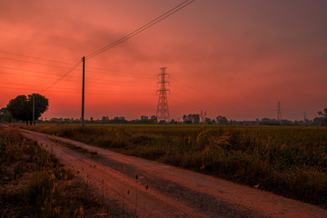 Blurred twilight evening background on rice paddies, with high voltage electricity towers passing...