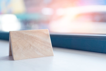 Wooden sign board on white table beside window with city view.
