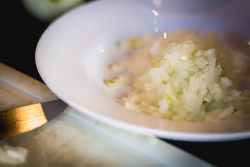 woman cuts onions on a white plastic board