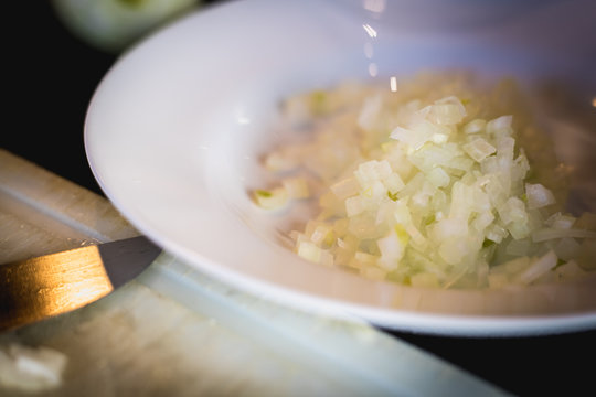 woman cuts onions on a white plastic board