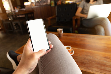 Mockup image blank white screen cell phone.man hand holding texting using mobile on desk at coffee shop.background empty space for advertise text.people contact marketing business,technology 