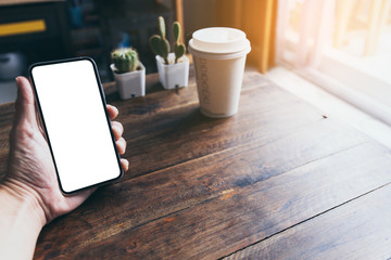 Mockup image blank white screen cell phone.man hand holding texting using mobile on desk at coffee shop.background empty space for advertise text.people contact marketing business,technology 