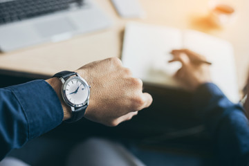 looking at luxury watch on hand check the time at workplace.concept for managing time organization...