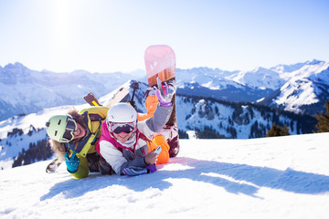 two girls with ski and snowboard posing on snow
