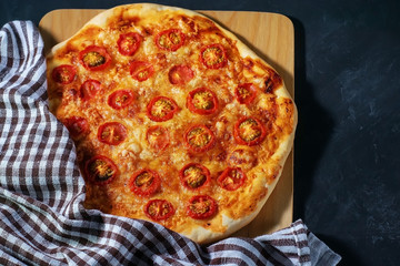 Freshly baked homemade pizza lies on a black wooden table