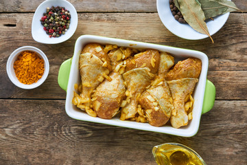 Raw chicken legs with spices in a ceramic form
