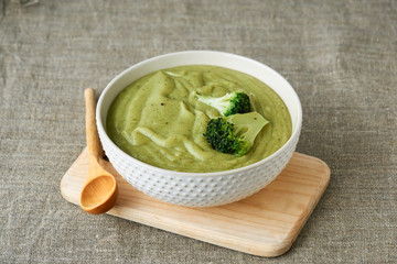 Broccoli cream soup in a white bowl on a textile background 