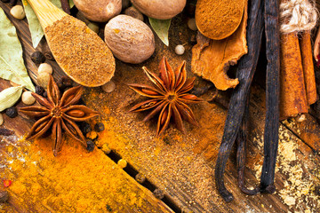 Vanilla sticks with different spices, nutmeg, cinnamon stick, anise on wooden background. Sweet spices. Copy space.