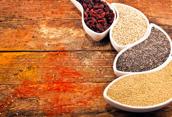 Goji berries, amaranth seeds, chia seeds, kinoa seeds in the ceramic bowls, nutritional supplement on wooden background. Text space.