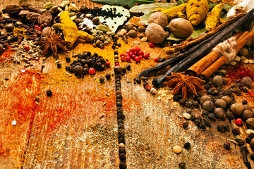 Different spices on wooden table, saffron, vanilla, nutmeg, anise, coriander, pepper on wooden background. Copy space.