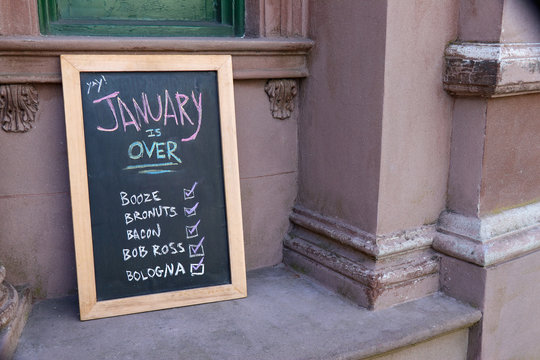 A humorous hand-lettered chalk board outside of a restaurant recommends several ways to celebrate the end of January.