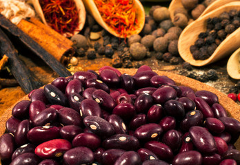 Red beans with different spices on wooden background.