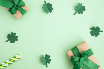 St Patrick's Day composition. Gift boxes, clover and festive decor on a light green background. Top view, flat lay, copy space