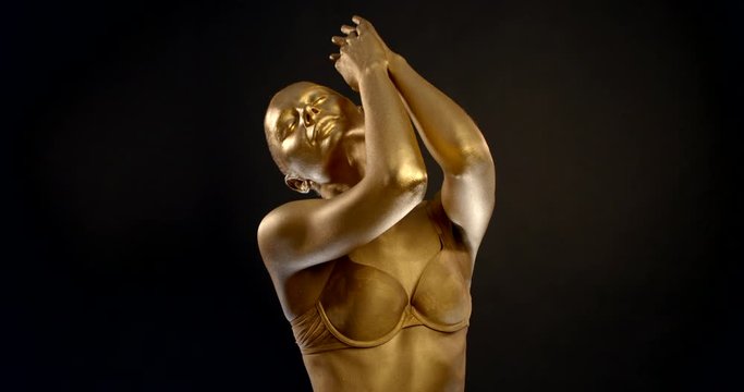 girl with golden skin wearing bra poses reflecting light