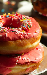 Dessert Glazer Donuts With colorful Sprinkles on the white plate on the black wooden background food sweet