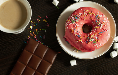 Dessert Glazer Donuts With colorful Sprinkles on the white plate with coffee and chocolate and Marshmallow on the black wooden background food sweet