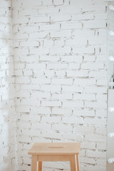Sitting empty wooden chair against the background of a white brick wall. Empty stool. Brick wall texture.