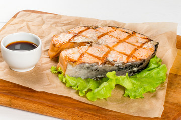 Grilled salmon steak with sauce on a wooden board