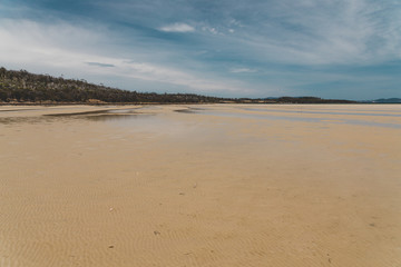 view of Dunalley Beach in Tasmania, Australia with sandbanks and shallow pristine water
