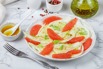 Delicious vegetarian fresh salad of fennel and grapefruit with a spicy dressing of citrus juice, olive oil, sweet mustard and spices. Vegetable Carpaccio . Selective focus, marble background