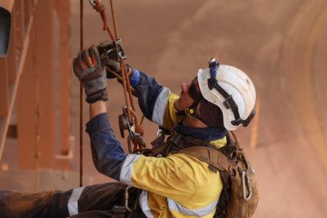 Rope access maintenance welder worker wearing fully safety equipment abseiling and sorting clipping inspecting his back up device into rope ready to abseiling down construction site Perth, Australia  © Kings Access