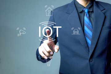 Internet of Things (IoT) concept. Business people press IoT solutions with symbols connected to common IoT icons. Smart home, cars, cctv, lamp.