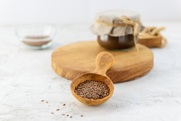 Flax seeds in a wooden spoon with flax paste on a wooden board.
