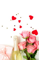 Valentine's day, birthday background. Bouquet of pink roses flowers, gift box ,champagne bottle and red hearts confetti isolated on white background with copy space. Top view flat lay