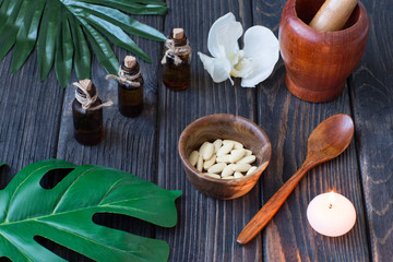 bottled oil, orchid, mortar, vitamins, candle on a wooden table