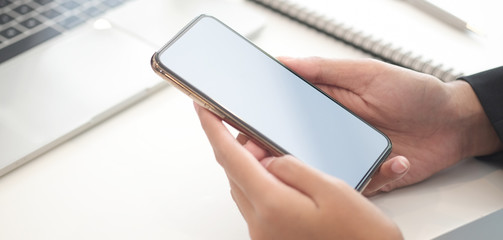 Cropped shot view of woman hands holding smart phone with blank copy space screen for your text message or information content, female reading text message on cell telephone during in urban setting. 