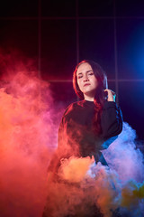 Portrait of chubby teen girl during photoshoot with colored smoke at night and black background