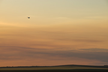 a field of Golden wheat in the rays of sunset and a plane flies over the field
