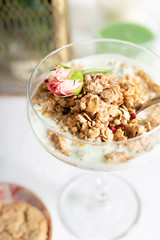 Breakfast concept. Light granola with greek yogurt in a glass goblet close-up on a white tablecloth. 