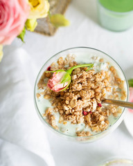 Breakfast concept. Light granola with greek yogurt in a glass goblet close-up on a white tablecloth. Top View Image