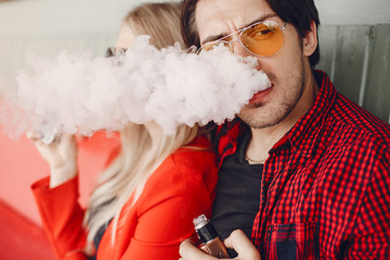 Stylish couple in a city. Two people use the electronic cigarette