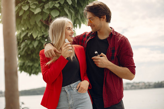 Stylish couple in a city. Two people use the electronic cigarette